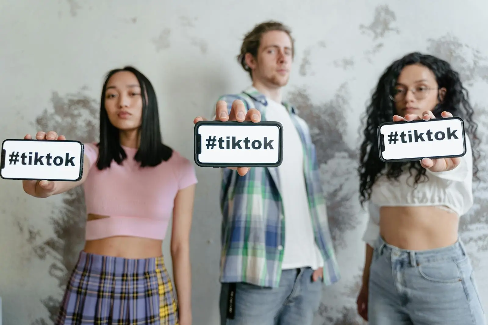 Group of Social Media Influencers holding phones with #tiktok indoors, showcasing social media culture.